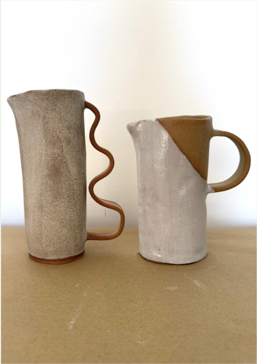 Two ceramic jugs side by side, one with a squiggle handle and one two-tone